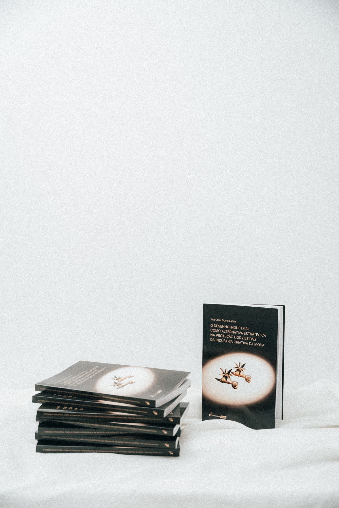 Livros empilhados e um exemplar em pé sobre fundo claro